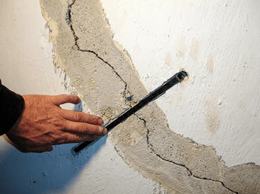 A wall with a large crack is being inspected by a professional in Rochester, NY